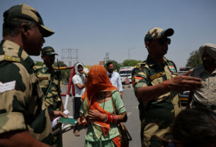 A Military Personnel With Border Security Force Checks Passport Of Pakistani Citizens As They Prepare To Leave India, At The Attari Wagah Border Crossing Near Amritsar